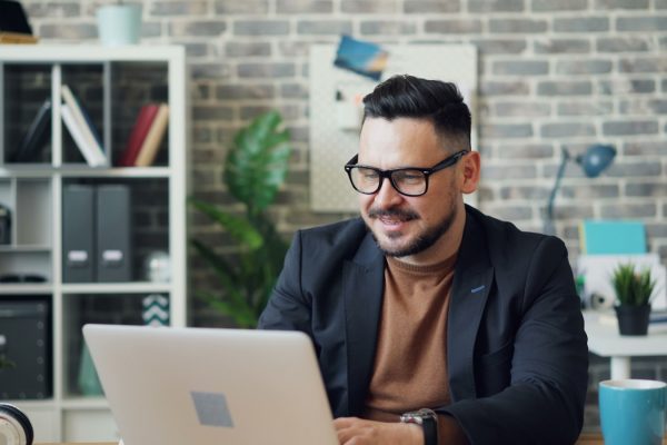 a man sitting at a desk using a laptop computer